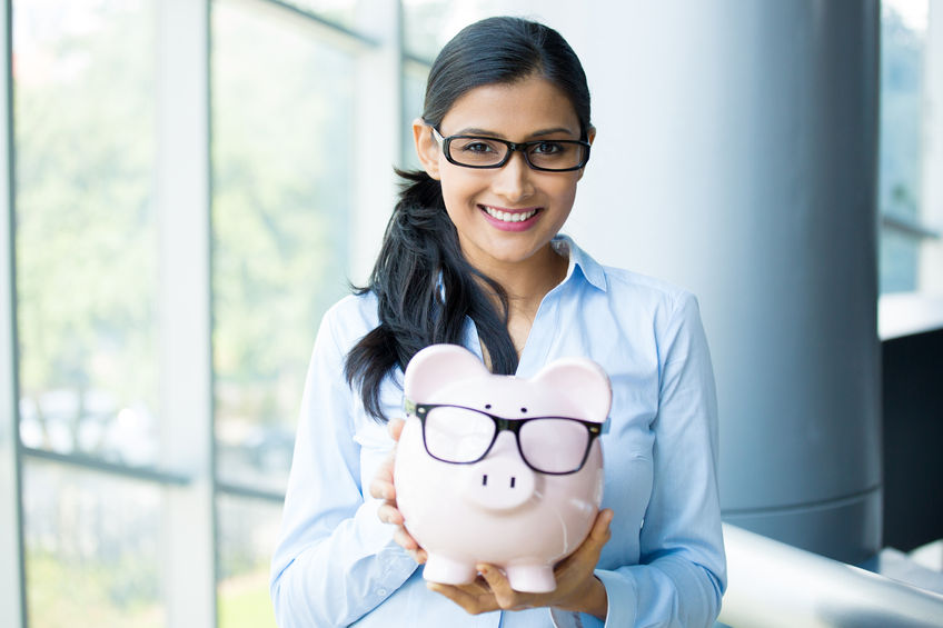 closeup portrait happy, smiling business woman, holding pink piggy bank, wearing big black glasses isolated indoors office background. financial budget savings, smart investment concept