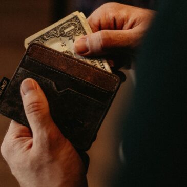 A person pulls a dollar out of his open wallet.