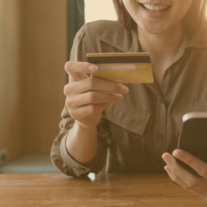 A woman smiling and holding her card after learning how to transfer high-interest rate balances to her Camino Visa Platinum with Rewards Credit Card. 